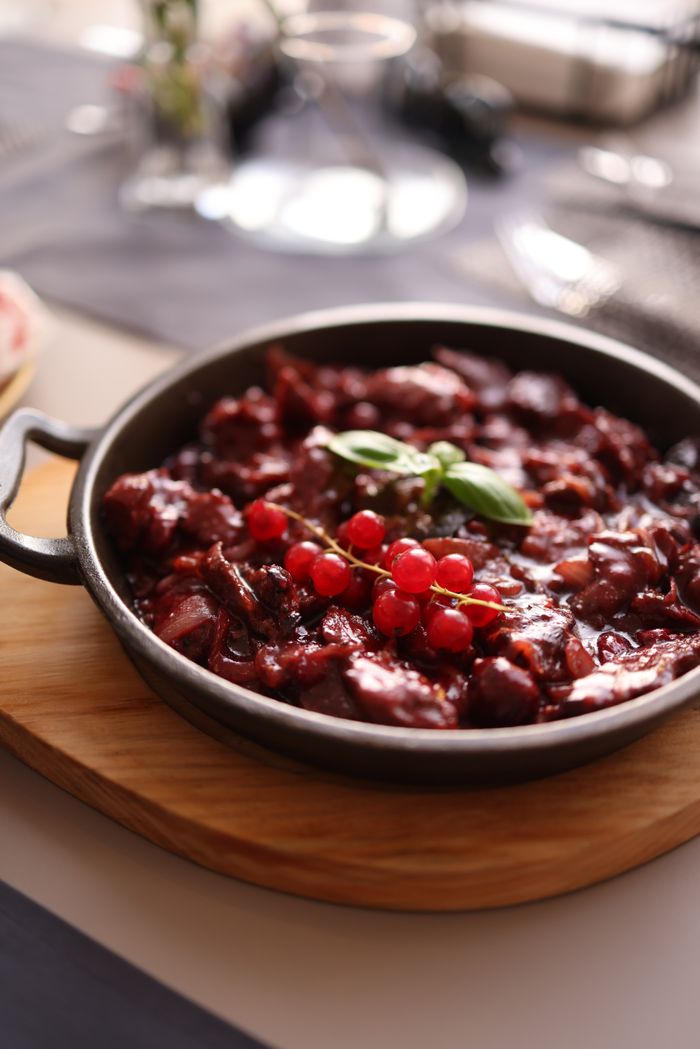 Savory beef stew garnished with cranberries served in a rustic bowl indoors.