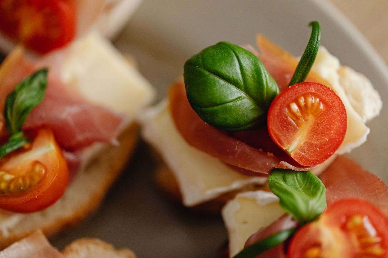 Close-up of fresh tomato and prosciutto on bruschetta, highlighting vibrant ingredients.