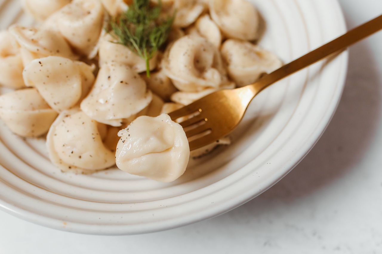 Delicious close-up of fresh dumplings with herbs on a white plate and fork.